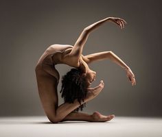 a woman is doing a handstand on the floor in front of a gray background