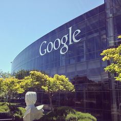 a building with a large google sign on it's side in front of trees and bushes