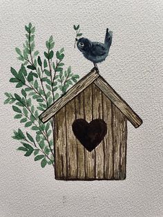 a bird sitting on top of a wooden bird house with a heart in the roof