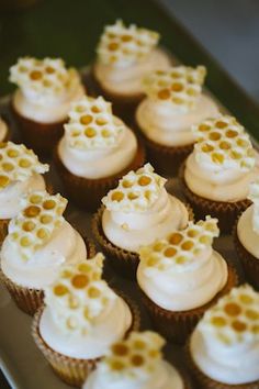 there are many cupcakes with white frosting and honeycomb decorations on them