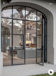 an arched glass door leading to a living room and dining area with couches in it