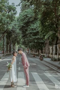 a bride and groom standing in the middle of a crosswalk with trees lining both sides