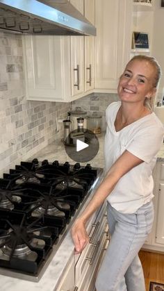 a woman standing in front of an oven smiling at the camera while holding her hand on the burner