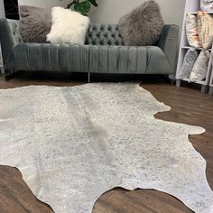 a living room with a gray couch and white cowhide rug