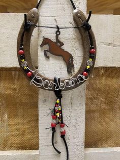 a cowgirl's necklace hanging on the side of a white building with a brown horse