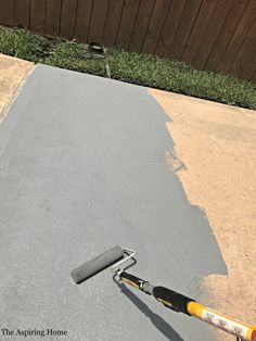 a paint roller laying on the ground next to a flat surface in front of a wooden fence