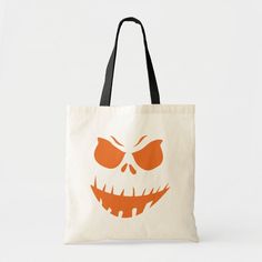 an orange halloween pumpkin face with big eyes tote bag on a white tablecloth