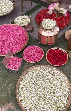 several bowls filled with flowers on top of a green table covered in pink and white petals