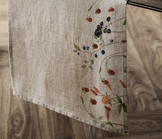 an embroidered piece of cloth hanging on a clothes line with wood flooring in the background