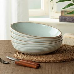 a stack of white plates sitting on top of a wooden table next to a knife and fork