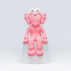 a pink teddy bear sitting on top of a white block with its eyes closed and one eye missing