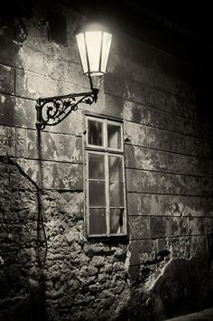 an old brick building with a lamp on the side