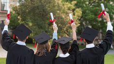 three graduates holding up their diplomas in the air