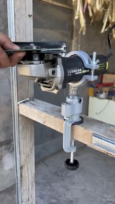 a person is holding a driller in front of a piece of wood with tools attached to it