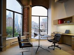 an office with a desk and chairs in front of a large window overlooking the city