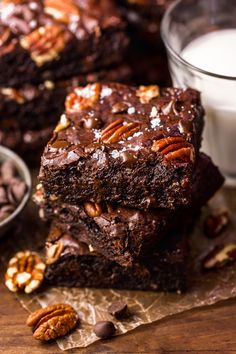 two brownies stacked on top of each other next to a glass of milk and pecans