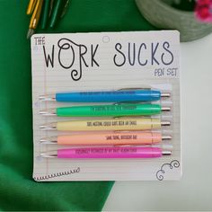 four pens with writing on them are sitting in a notepad next to some flowers