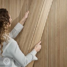 a woman is leaning against the wall with her hand on the wood slats behind her