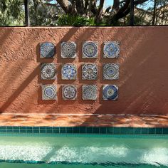 several plates are arranged on the wall next to a swimming pool