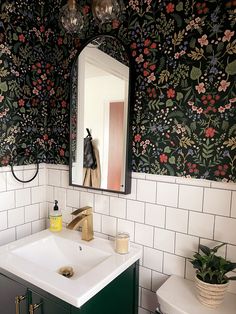 a bathroom sink sitting under a mirror next to a green cabinet and white tiled walls