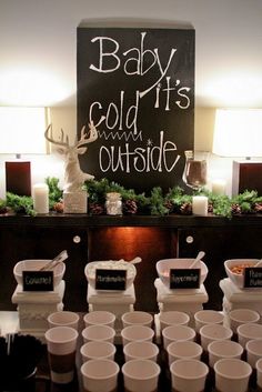 the baby it's cold outside sign is displayed in front of cups and candles