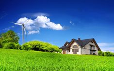 a house in the middle of a green field with a wind turbine on top of it