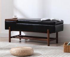 a black leather bench sitting on top of a white rug next to a wooden table