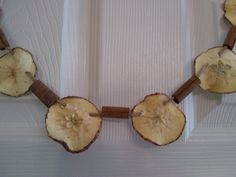 an apple slice is attached to a wooden bead with leaves and flowers on it