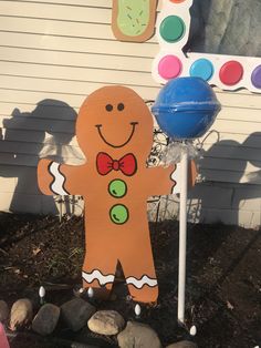 a wooden ginger with a bow tie standing in front of a building and some rocks