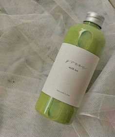 a bottle of green liquid sitting on top of a white cloth