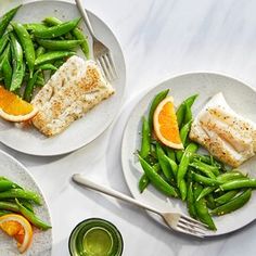 three plates with fish, green beans and orange slices