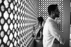 black and white photograph of two people standing in front of a wall with lattice design