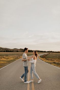 two people walking down the middle of an empty road with one person holding his hand