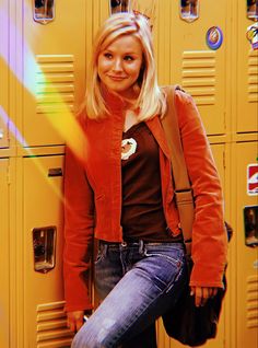 a woman standing in front of lockers with her hand on her hip and smiling