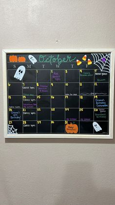 a chalkboard calendar hanging on the wall in front of a door decorated for halloween