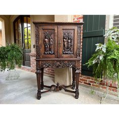 an old wooden cabinet sitting on the side of a building next to a potted plant