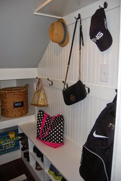 several purses and hats are hanging on the wall in this small room with white paneling