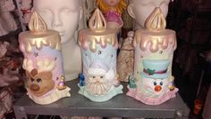 some very cute looking candles on a shelf in front of many other dolls and figurines