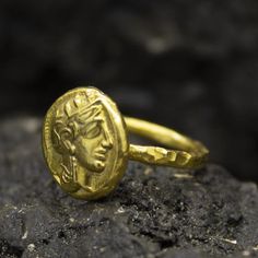 a gold ring with an image of a man's head on it sitting on top of a rock