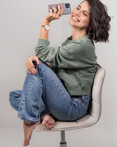 a woman sitting on top of a chair taking a selfie