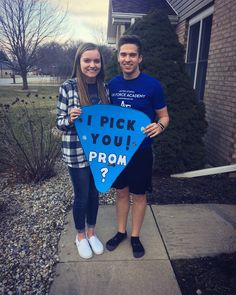 two people holding a sign that says i pick you prom