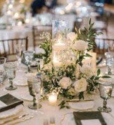 the table is set with white flowers and candles for an elegant centerpieces display