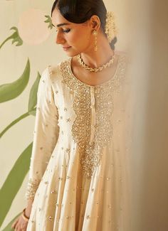 This beautiful ivory and gold Chanderi silk Kurta set exudes grace and elegance, featuring intricate embroidery adorned with sequins, pearls, and cutdana work. The anarkali top has a regal flair with delicate embellishments along the neckline, sleeves, and hemline, adding a luxurious touch to the traditional design. The flowy silhouette is paired with matching straight-cut trousers, offering both comfort and style. Completing the ensemble is a matching ivory dupatta embellished with gold embroid Short Anarkali, Anarkali Tops, Cutdana Work, Silk Kurta Set, Pearl Work, Blossom Season, Emb Designs, Dresses Traditional, Pearl Embroidery