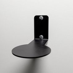 a black shelf mounted to the side of a wall with two metal hooks on it