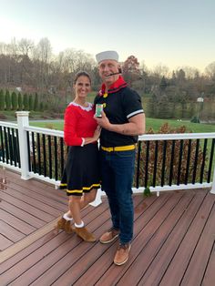 a man and woman dressed in costumes standing on a deck with their arms around each other