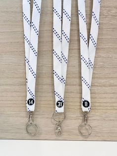 three white lanyards with black numbers on them