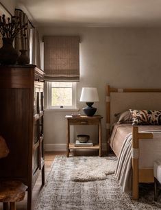 a bed sitting next to a wooden dresser in a bedroom on top of a hard wood floor