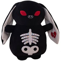 a black stuffed animal with red eyes and white ears, has a skeleton on it's back