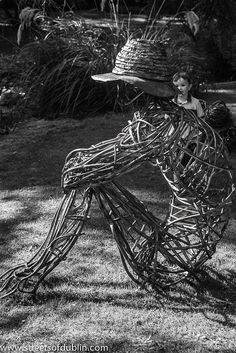 black and white photograph of a child with a hat on top of a wire sculpture