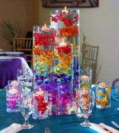 there is a tall vase with candles in it on the table next to many glasses